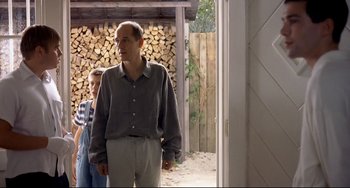 Movie still from “Funny Games” (1997), directed by Michael Haneke – A man standing in front of a door with another man standing behind him; Medium shot, Over the shoulder angle