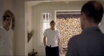 Movie still from “Funny Games” (1997), directed by Michael Haneke – A man in a white shirt and black pants standing in a room; Medium shot, Over the shoulder angle