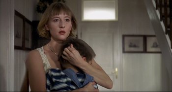 Movie still from “Funny Games” (1997), directed by Michael Haneke – A woman holding a child in her arms in a room; Close Up shot, Low angle