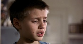 Movie still from “Funny Games” (1997), directed by Michael Haneke – A young boy with a tear in his eye; Close Up shot, Low angle