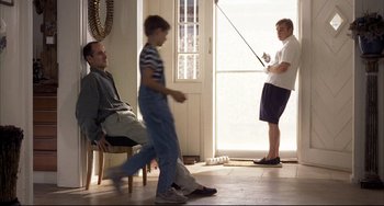 Movie still from “Funny Games” (1997), directed by Michael Haneke – A man and a boy are playing a game with a stick; Wide shot, Low angle