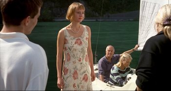 Movie still from “Funny Games” (1997), directed by Michael Haneke – A woman standing on a boat in front of a group of people; Medium shot, Over the shoulder angle