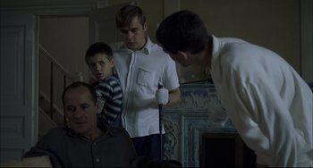 Movie still from “Funny Games” (1997), directed by Michael Haneke – A group of people standing around a room; Medium shot, Over the shoulder angle