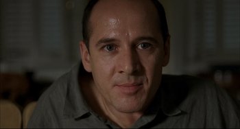 Movie still from “Funny Games” (1997), directed by Michael Haneke – A person wearing a gray shirt; Close Up shot, Low angle