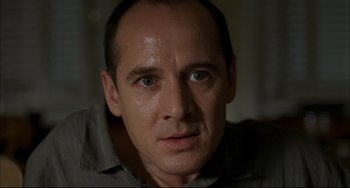 Movie still from “Funny Games” (1997), directed by Michael Haneke – A person with a shirt on looking at the camera; Close Up shot, Low angle