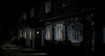 Movie still from “Funny Games” (1997), directed by Michael Haneke – A house with shutters lit up at night time; Extreme Wide shot, High angle