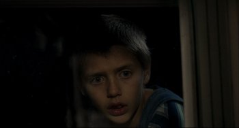 Movie still from “Funny Games” (1997), directed by Michael Haneke – A young boy is looking at the camera; Close Up shot, Over the shoulder angle