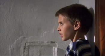 Movie still from “Funny Games” (1997), directed by Michael Haneke – A young boy is looking into the distance; Close Up shot, Low angle