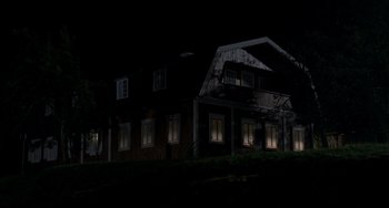 Movie still from “Funny Games” (1997), directed by Michael Haneke – A house that is lit up at night time; Extreme Wide shot, Low angle