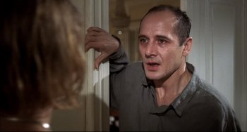 Movie still from “Funny Games” (1997), directed by Michael Haneke – A man is leaning against a wall with his hand on the wall; Close Up shot, Over the shoulder angle