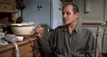 Movie still from “Funny Games” (1997), directed by Michael Haneke – A man sitting in front of a bowl of food; Medium shot, Low angle