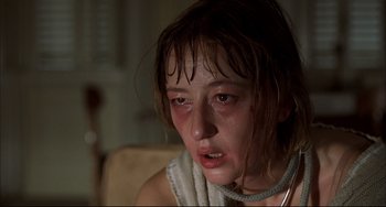 Movie still from “Funny Games” (1997), directed by Michael Haneke – A young woman with a bruised face sitting on a couch; Close Up shot, Low angle