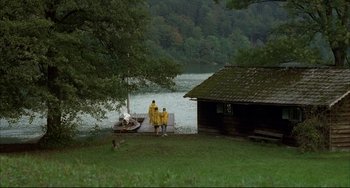 Movie still from “Funny Games” (1997), directed by Michael Haneke – Two men in yellow jackets standing on a dock; Extreme Wide shot, High angle