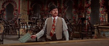 Movie still from “Funny Girl” (1968), directed by William Wyler – A man in a hat and tie standing in front of chairs; Medium shot, Over the shoulder angle