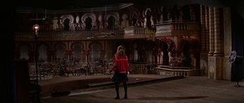 Movie still from “Funny Girl” (1968), directed by William Wyler – A woman standing on a stage in front of a building; Extreme Wide shot, High angle