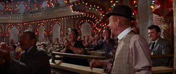 Movie still from “Funny Girl” (1968), directed by William Wyler – An old man and woman in a crowd of people in front of lights; Wide shot, Low angle