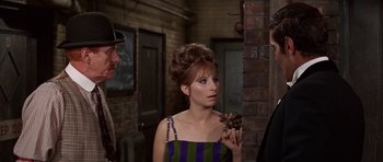 Movie still from “Funny Girl” (1968), directed by William Wyler – A woman in a striped dress is holding grapes in her hand; Medium shot, Over the shoulder angle