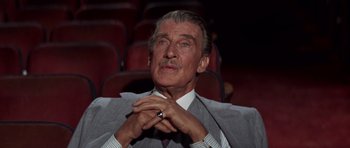 Movie still from “Funny Girl” (1968), directed by William Wyler – An older man in a gray suit and white shirt is sitting in an empty theater; Close Up shot, Low angle