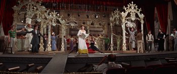 Movie still from “Funny Girl” (1968), directed by William Wyler – A group of people on a stage with a woman in a white dress; Wide shot, Low angle