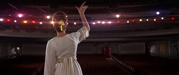 Movie still from “Funny Girl” (1968), directed by William Wyler – A woman in a white dress waves at the audience; Wide shot, Low angle