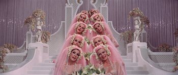 Movie still from “Funny Girl” (1968), directed by William Wyler – A group of women in pink dresses and white flowers in their hair; Medium shot, Overhead angle