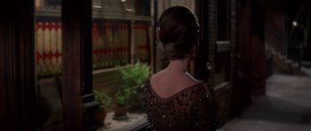 Movie still from “Funny Girl” (1968), directed by William Wyler – A woman in a dress looking out of a window; Medium shot, Over the shoulder angle