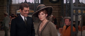 Movie still from “Funny Girl” (1968), directed by William Wyler – A woman wearing a hat standing next to a man; Medium shot, Over the shoulder angle