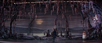 Movie still from “Funny Girl” (1968), directed by William Wyler – A man standing in front of a stage with trees and flowers; Extreme Wide shot, High angle