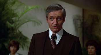 Movie still from “Futureworld” (1976), directed by Richard T. Heffron – A man in a suit and tie standing in front of a plant; Close Up shot, Low angle