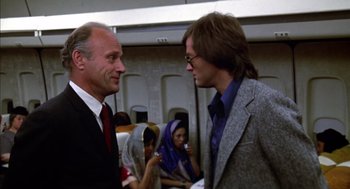 Movie still from “Futureworld” (1976), directed by Richard T. Heffron – Two men are talking on a plane while others look on; Medium shot, Low angle