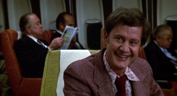 Movie still from “Futureworld” (1976), directed by Richard T. Heffron – A man in a suit and tie sitting in a chair; Medium shot, Over the shoulder angle