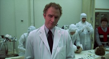 Movie still from “Futureworld” (1976), directed by Richard T. Heffron – A man wearing a lab coat and tie in front of a group of people; Medium shot, Over the shoulder angle