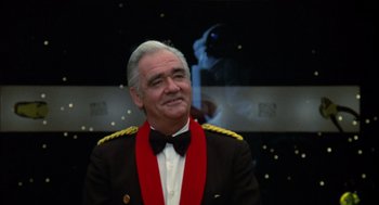 Movie still from “Futureworld” (1976), directed by Richard T. Heffron – An older man in a military uniform and a bow tie; Close Up shot, Over the shoulder angle