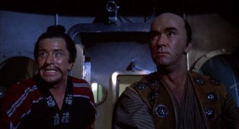 Movie still from “Futureworld” (1976), directed by Richard T. Heffron – Two men standing next to each other in a room; Medium shot, Low angle