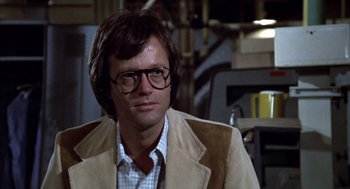 Movie still from “Futureworld” (1976), directed by Richard T. Heffron – A person wearing glasses and a jacket; Close Up shot, Over the shoulder angle