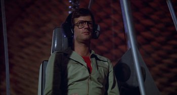 Movie still from “Futureworld” (1976), directed by Richard T. Heffron – A man wearing headphones sitting in an airplane seat; Medium shot, Overhead angle