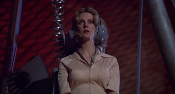 Movie still from “Futureworld” (1976), directed by Richard T. Heffron – A woman standing in front of a chair with a phone on her head; Medium shot, Low angle