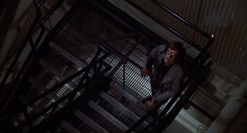 Movie still from “Futureworld” (1976), directed by Richard T. Heffron – A man standing on top of a set of metal stairs; Wide shot, Overhead angle