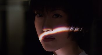 Movie still from “Gamera 3: Revenge of Iris” (1999), directed by Shûsuke Kaneko – A woman's face with light shining on it; Close Up shot, Low angle