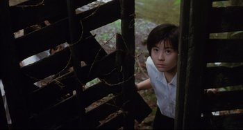 Movie still from “Gamera 3: Revenge of Iris” (1999), directed by Shûsuke Kaneko – A young woman standing next to a wooden fence; Medium shot, High angle