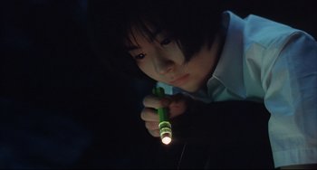 Movie still from “Gamera 3: Revenge of Iris” (1999), directed by Shûsuke Kaneko – A young boy holding a flashlight in a dark room; Close Up shot, High angle