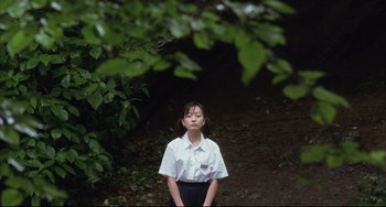 Movie still from “Gamera 3: Revenge of Iris” (1999), directed by Shûsuke Kaneko – A young girl standing in front of some trees; Medium shot, High angle