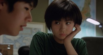 Movie still from “Gamera 3: Revenge of Iris” (1999), directed by Shûsuke Kaneko – A young asian girl sitting in front of another young man; Close Up shot, Over the shoulder angle