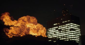 Movie still from “Gamera 3: Revenge of Iris” (1999), directed by Shûsuke Kaneko – An explosion is seen in front of a large building; Extreme Wide shot, Low angle