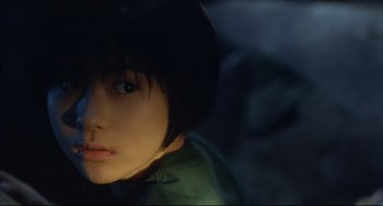 Movie still from “Gamera 3: Revenge of Iris” (1999), directed by Shûsuke Kaneko – A young woman with short black hair looking at the camera; Close Up shot, High angle