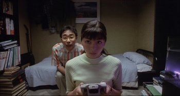 Movie still from “Gamera 3: Revenge of Iris” (1999), directed by Shûsuke Kaneko – A man and a woman playing a video game; Medium shot, High angle
