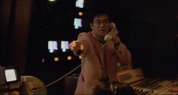 Movie still from “Gamera 3: Revenge of Iris” (1999), directed by Shûsuke Kaneko – A man in a pink jacket is holding a remote control; Medium shot, Low angle