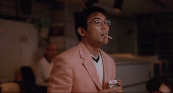 Movie still from “Gamera 3: Revenge of Iris” (1999), directed by Shûsuke Kaneko – A man in a pink suit smoking a cigarette; Close Up shot, Low angle