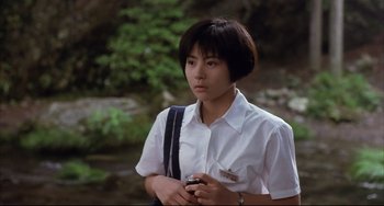 Movie still from “Gamera 3: Revenge of Iris” (1999), directed by Shûsuke Kaneko – A woman in a white shirt is holding a camera; Medium shot, Low angle
