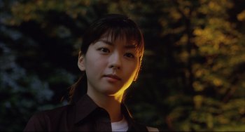 Movie still from “Gamera 3: Revenge of Iris” (1999), directed by Shûsuke Kaneko – A young asian woman in a dark forest; Close Up shot, Low angle